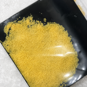 Matte black sachet pouch with a transparent front window showing yellow crystalline powder inside